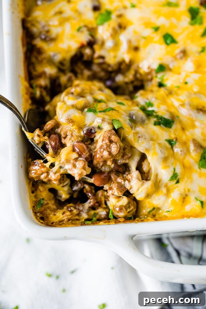 Weekly Meal Plan: Sept 18–24 with Simple Dinners and Prep Tips 3 a white casserole dish with a Mexican cheesy ground beef and rice casserole being scooped up with a large spoon