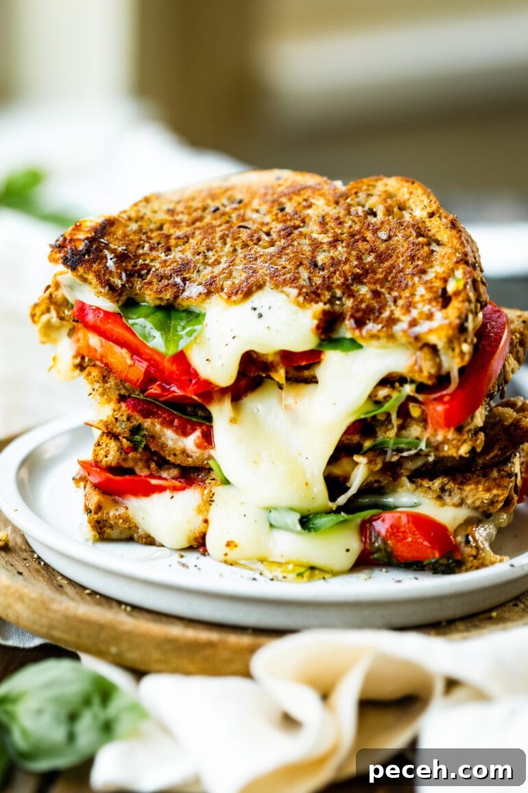 Weekly Meal Plan: Sept 18–24 with Simple Dinners and Prep Tips 5 a photo of several halved grilled cheese sandwiches stacked on top of each other so you can see the cheese melting out of it and the layers of tomato and fresh basil.