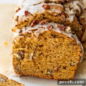 Moist Butternut Squash Loaf Recipe for Fall Baking 15 overhead view of a sliced loaf of butternut squash bread topped with a white glaze and pecans.