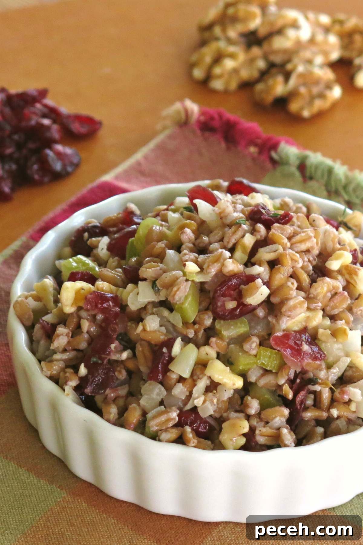 Hearty Farro Pilaf with Roasted Vegetables and Herbs 4 Farro Stuffing Pilaf in a serving bowl with walnuts and cranberries behind it.