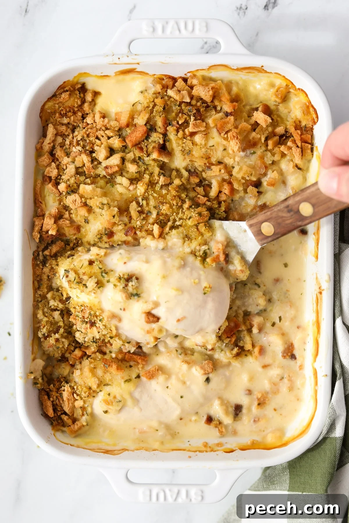 Creamy Swiss-Style Chicken Casserole with Mushrooms and Cheese 13 Lifting chicken and stuffing from a casserole dish.