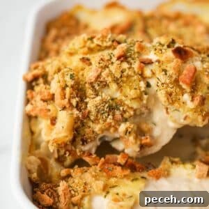 Creamy Swiss-Style Chicken Casserole with Mushrooms and Cheese 17 Lifting a piece of chicken and stuffing from a baking dish.