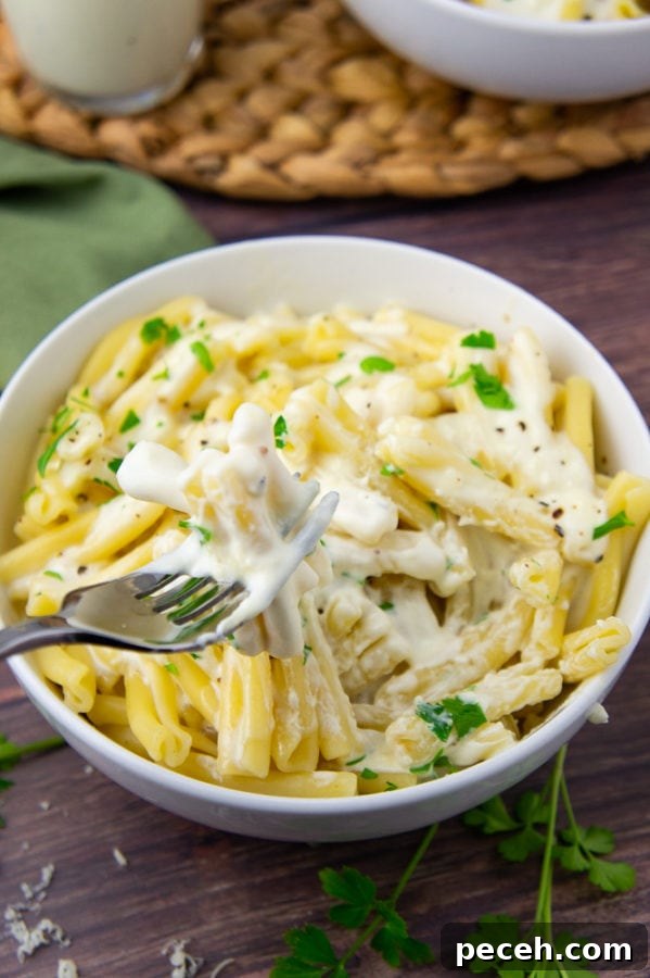 Creamy Asiago Sauce Recipe for Pasta and Vegetables 6 A fork with creamy sauced noodles on it over a bowl of pasta