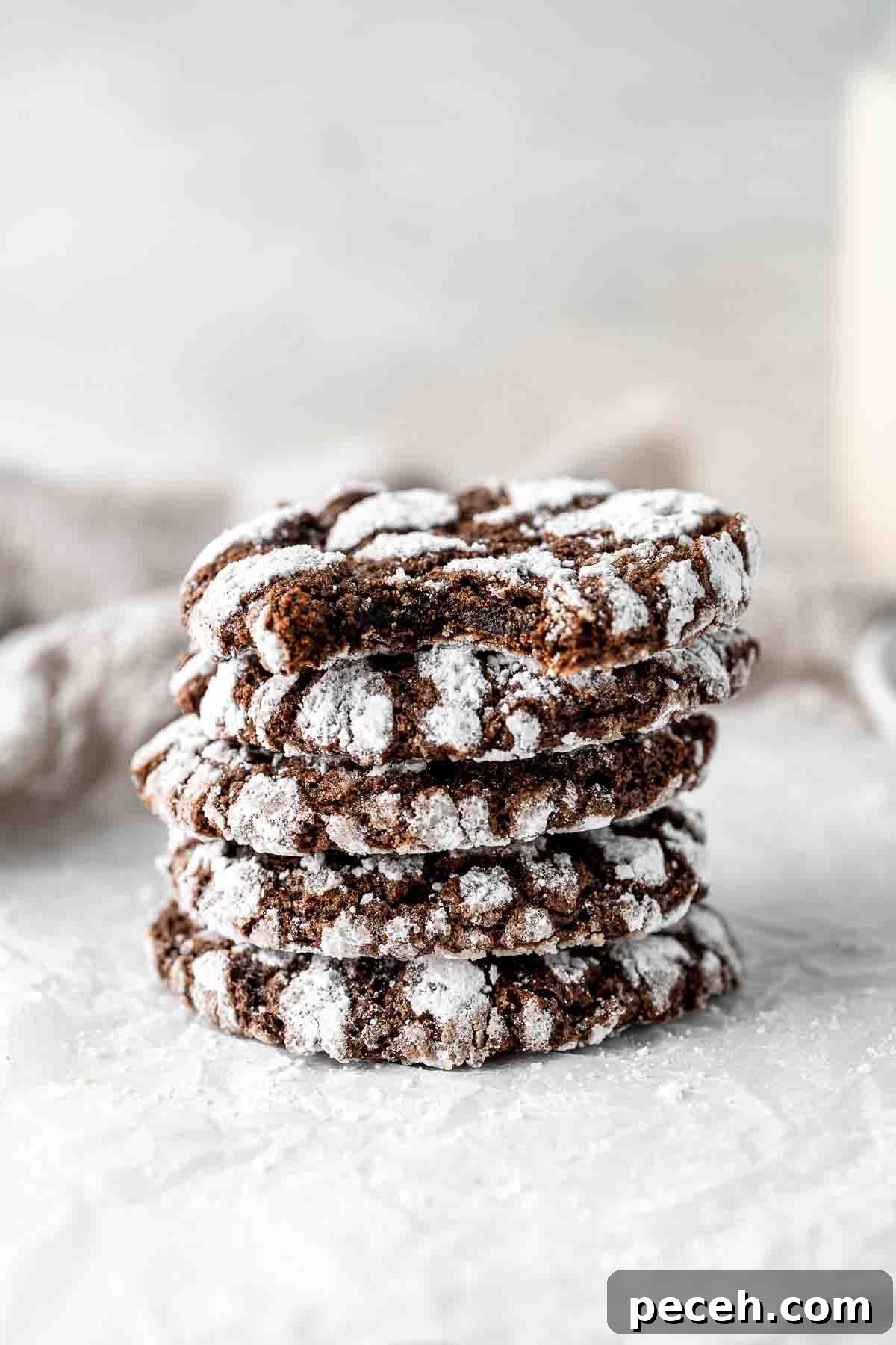 Fudgy Chocolate Crinkle Cookies Recipe 11 Stack of chocolate crinkle cookies with the top one having a bite taken.