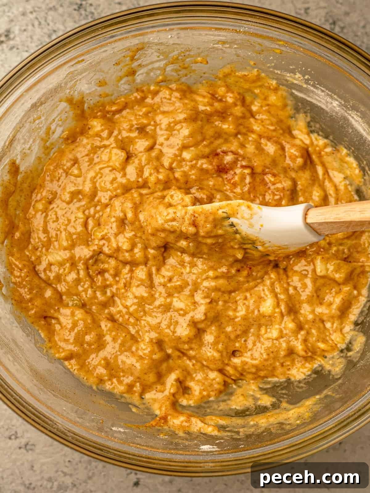 Batter in a clear bowl with a spatula in it.