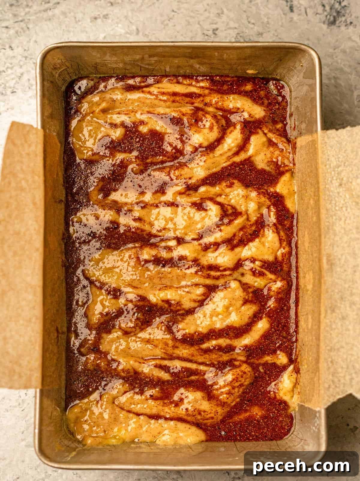 Batter in a loaf pan lined with parchment paper.