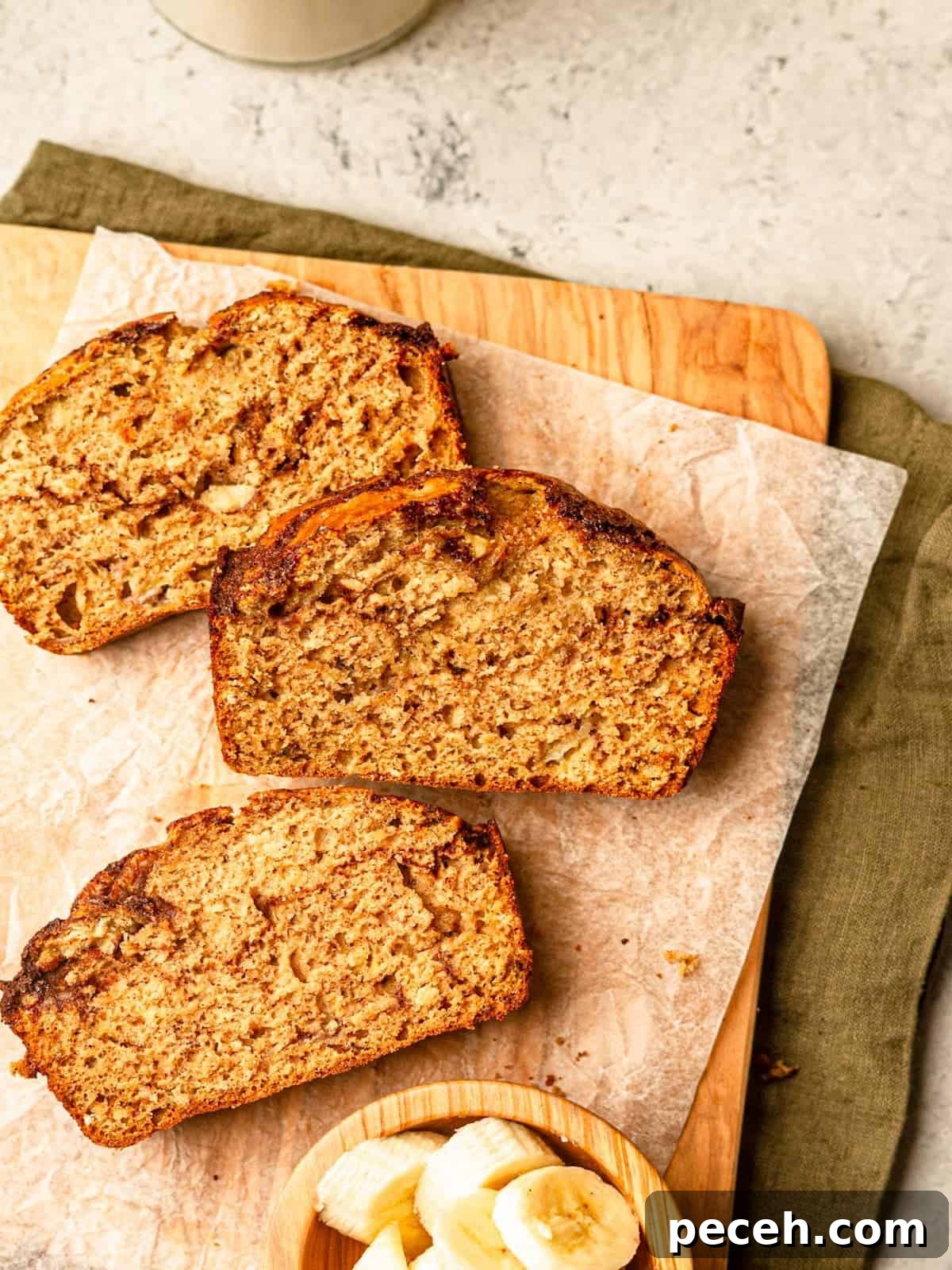 A cutting board on a green napkin topped with slices of banana bread.