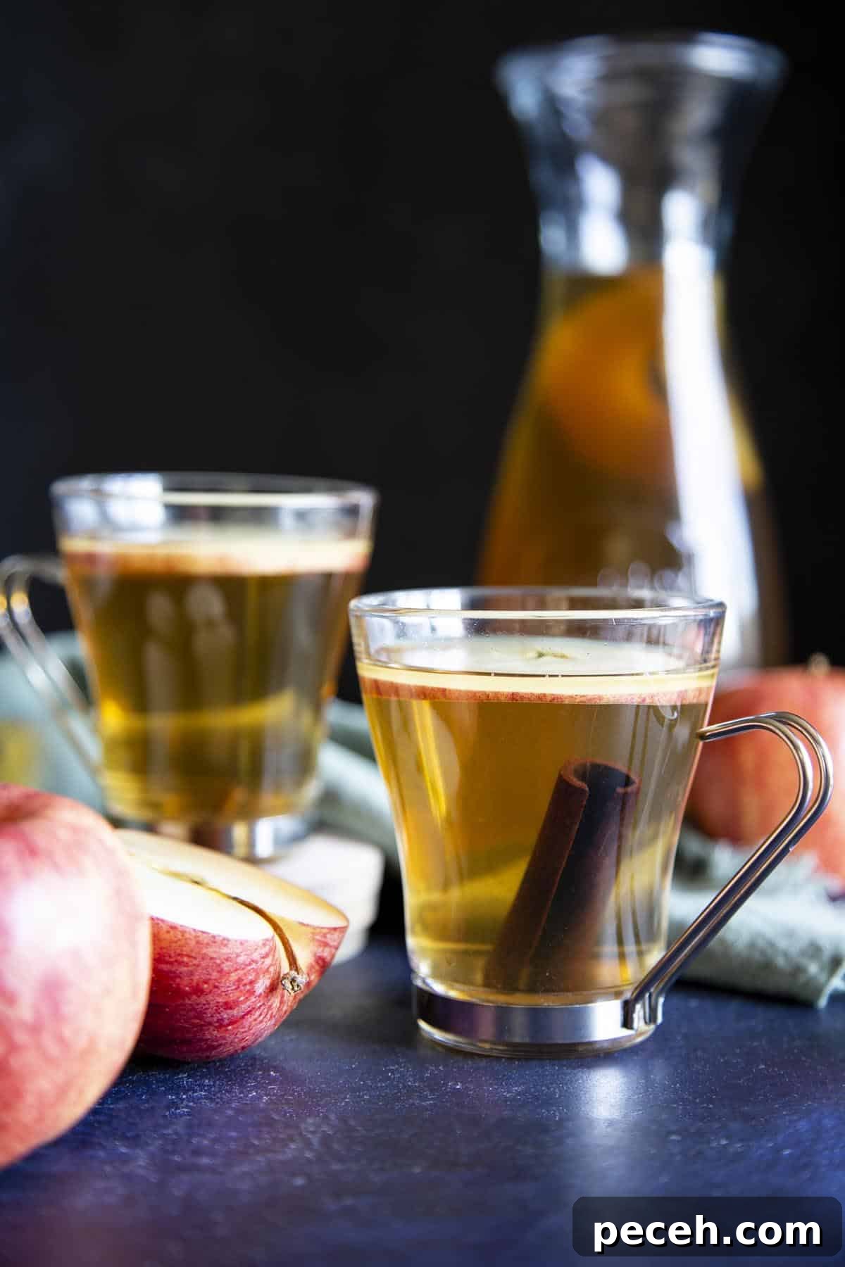 2 glasses of apple ciders next to some apple and a serving jug.