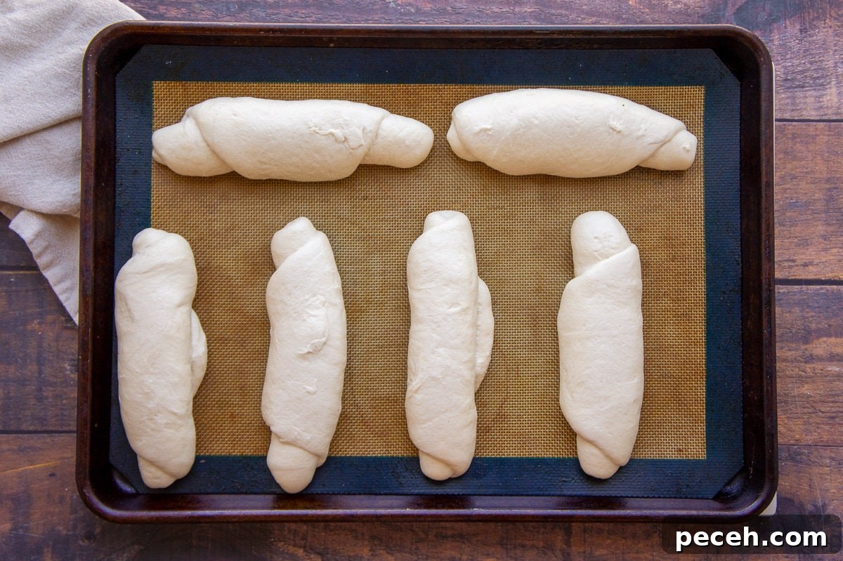 How to Make Soft Homemade Hot Dog Buns 4 homemade hot dog buns, shaped on a baking sheet