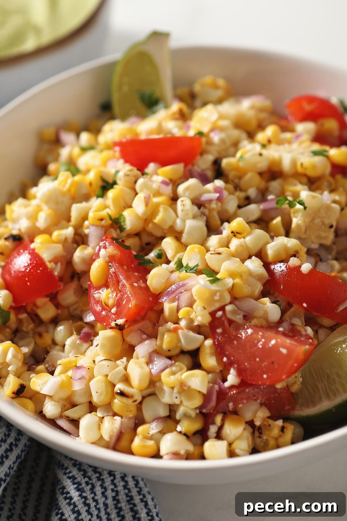 Smoky Charred Corn Salsa with Cilantro and Lime 7 Close up of Charred Corn Salsa with tomatoes, limes and more in a white bowl