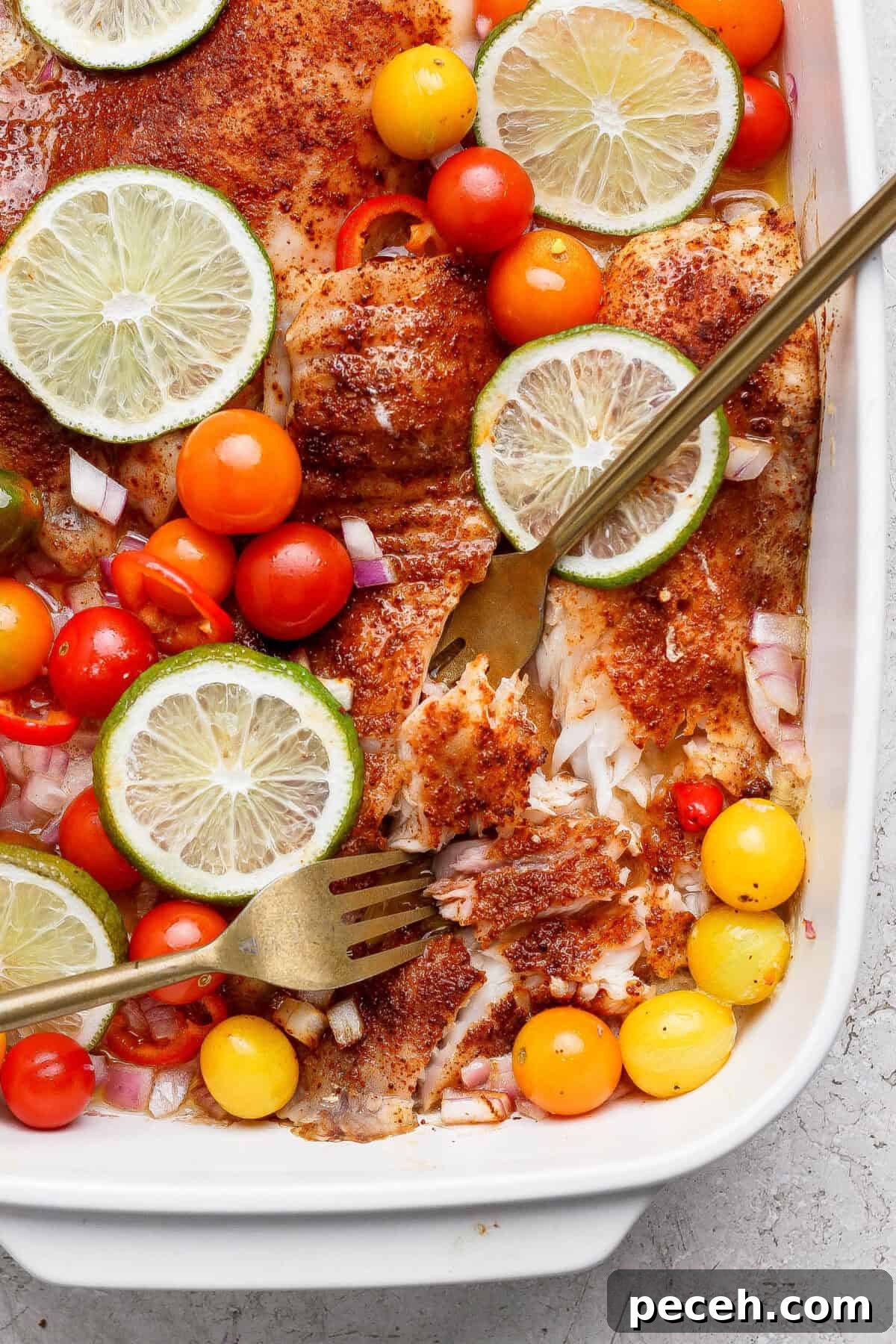 Baked Chile-Lime Fish Tacos with Tangy Cilantro Slaw 4 Baked fish fillets topped with sliced lime, cherry tomatoes, diced red onion, and spices, served in a white baking dish with two forks.