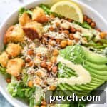 Crispy Roasted Chickpea Caesar Salad 14 roasted chickpea caesar salad with avocado and croutons in a white bowl.