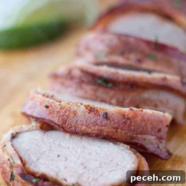Smoked Pork Loin Recipe for Tender, Flavorful Meat 14 Bacon wrapped pork tenderloin cut into slices on wood cutting board with cilantro and lime garnish