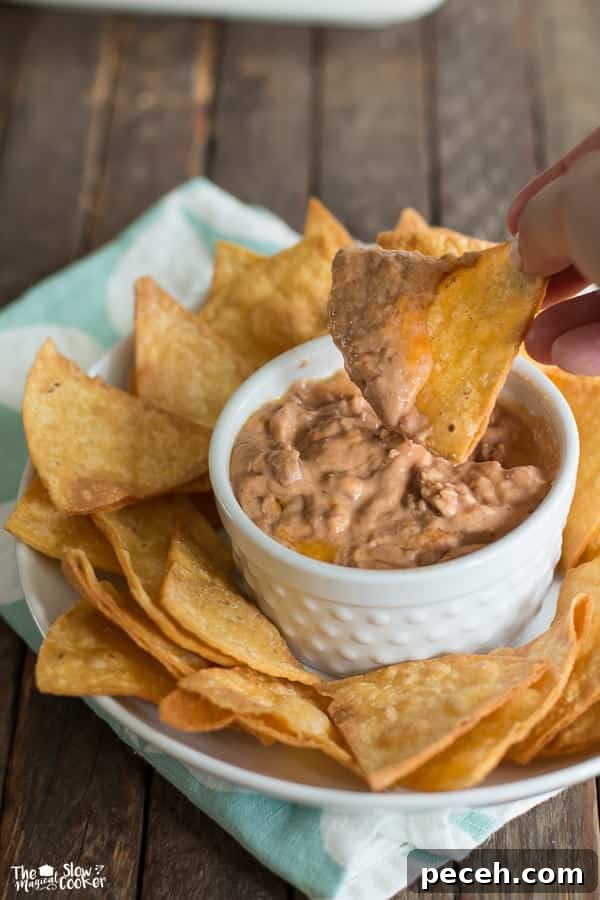 Creamy Bean and Cheese Dip for Parties 4 chip being dipped in small white ramekin.