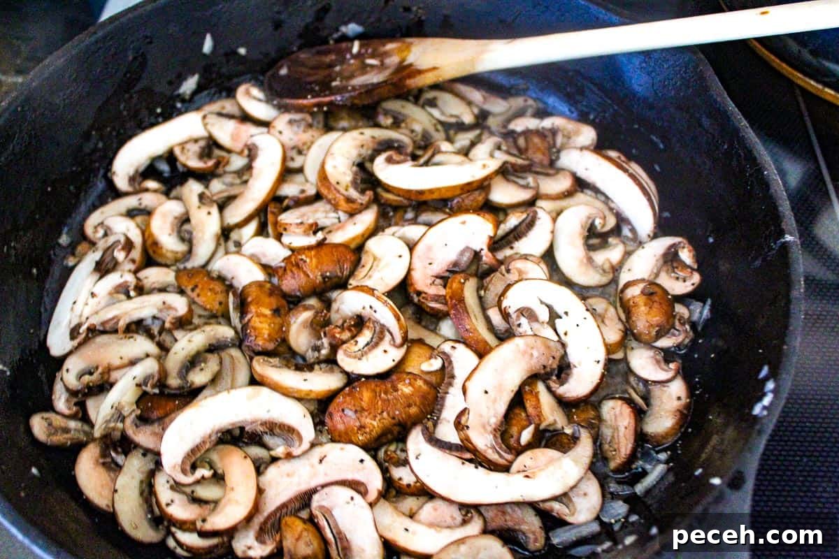 Creamy Mushroom Sauce for Pasta, Steak, and Veggies 3 Sliced mushrooms sauteing in black skillet.