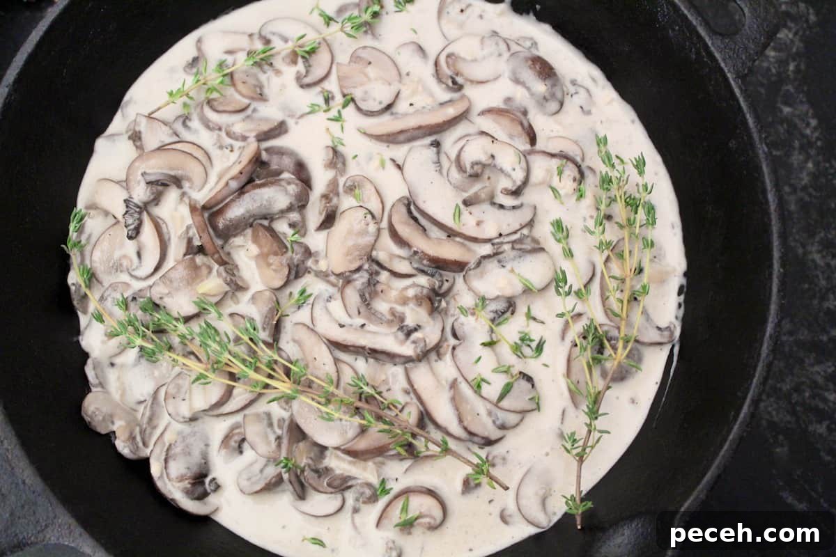 Creamy Mushroom Sauce for Pasta, Steak, and Veggies 4 Creamy mushroom sauce in saucepan with fresh thyme sprigs.
