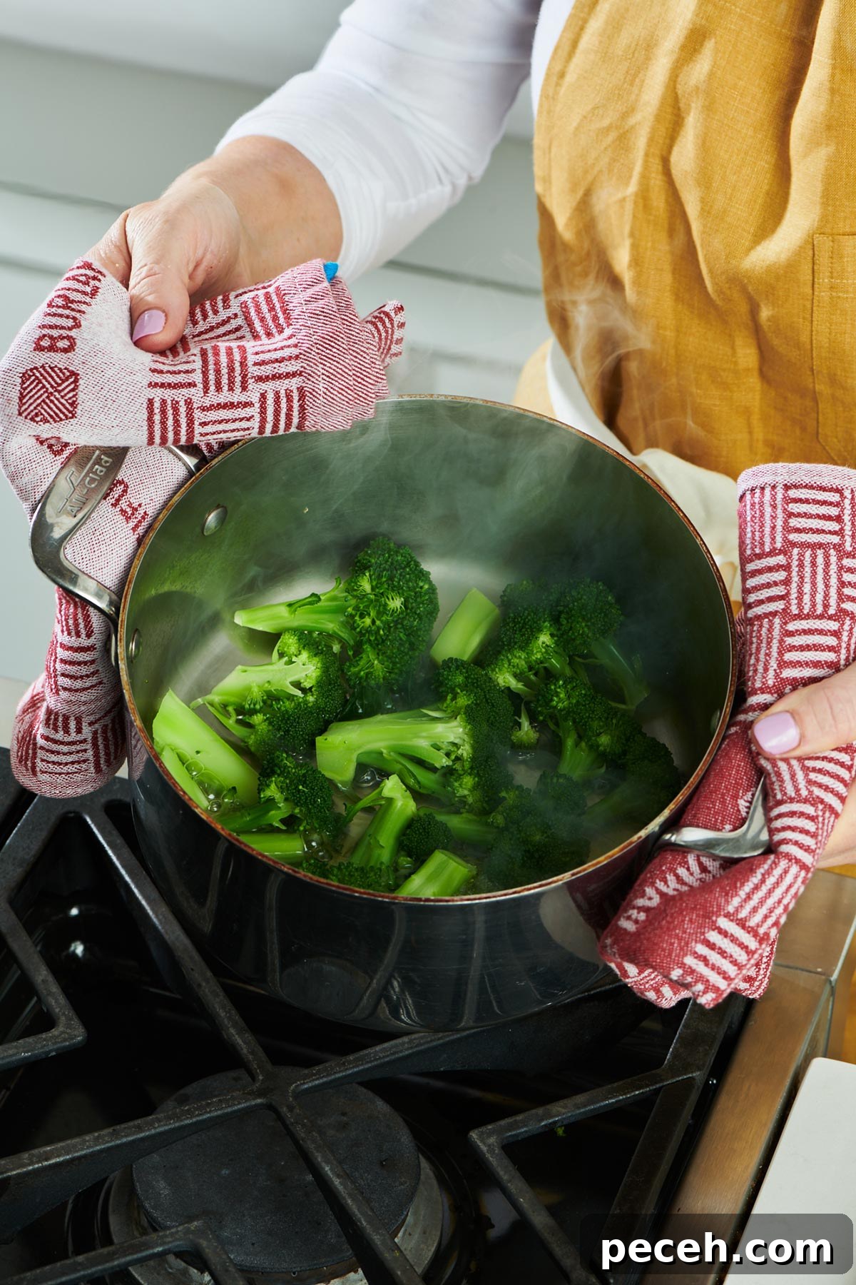 Stovetop Steamed Broccoli for Tender, Vibrant Florets 2 Woman holding pot of steamed broccoli over stove.
