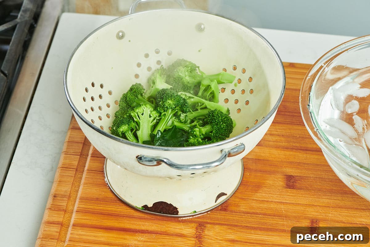 Stovetop Steamed Broccoli for Tender, Vibrant Florets 5 Steamed broccoli in colander on cutting board.