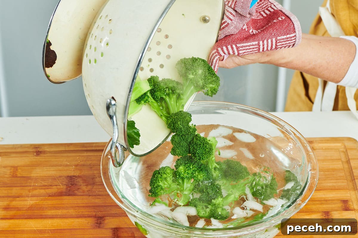 Stovetop Steamed Broccoli for Tender, Vibrant Florets 6 Pouring steamed broccoli into ice water bath.